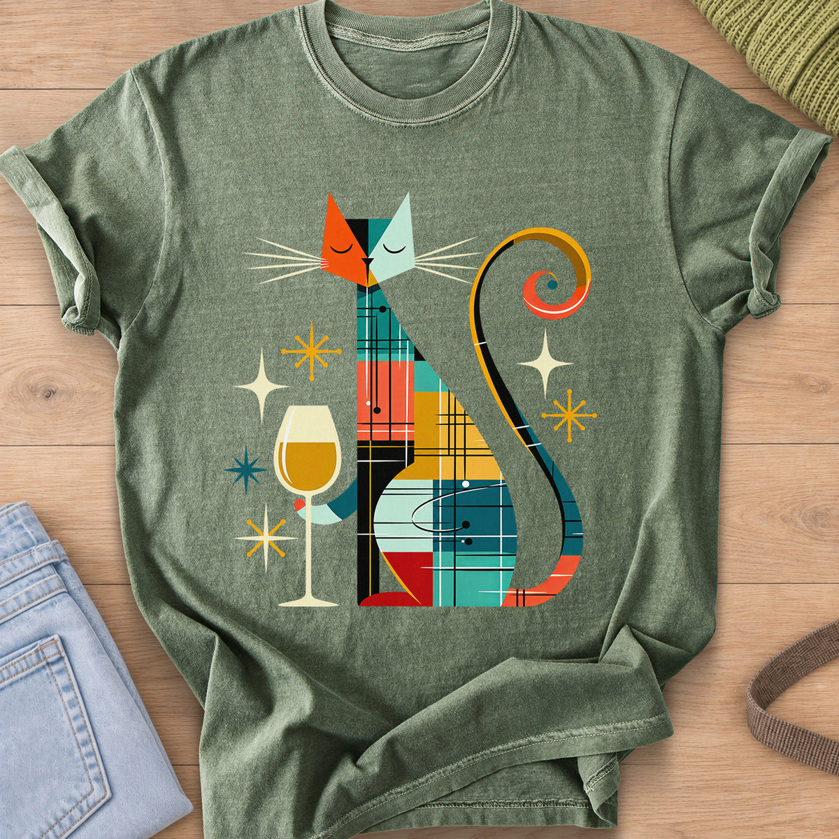 Geometric patchwork cat with closed eyes holding a wine glass among starbursts on a Moss T-Shirt