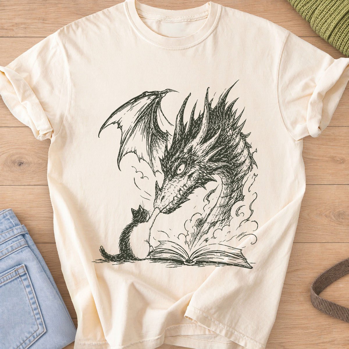 Small cat reaching up to a winged dragon's snout over an open book with smoke, dark charcoal ink on an Ivory T-Shirt