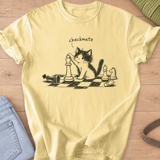 Fluffy kitten with a paw on a chess king, toppled pieces on a board, "checkmate", dark charcoal ink on a Butter T-Shirt