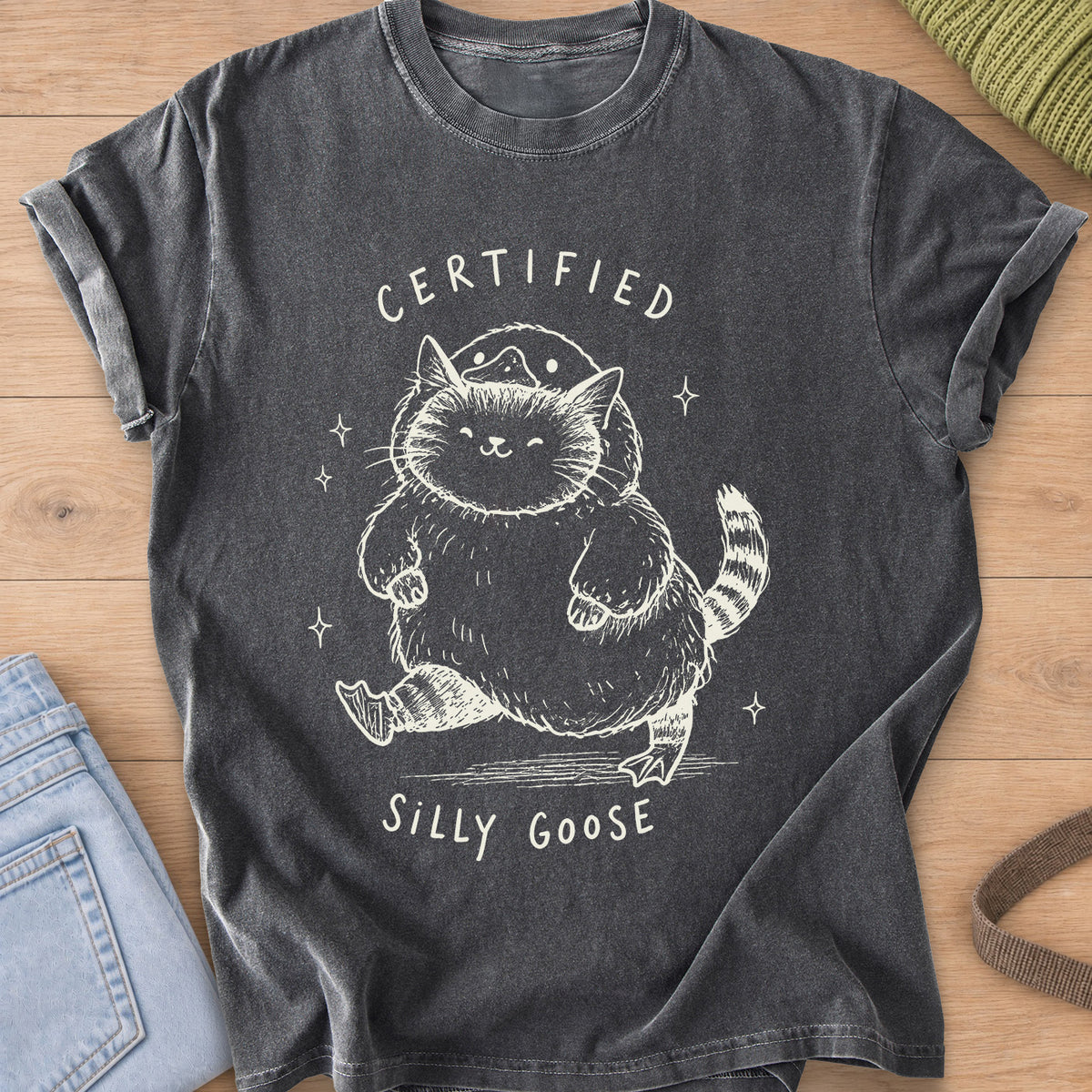 Chubby tabby cat in a goose costume walking among sparkles, "Certified Silly Goose", cream ink on a Pepper T-Shirt