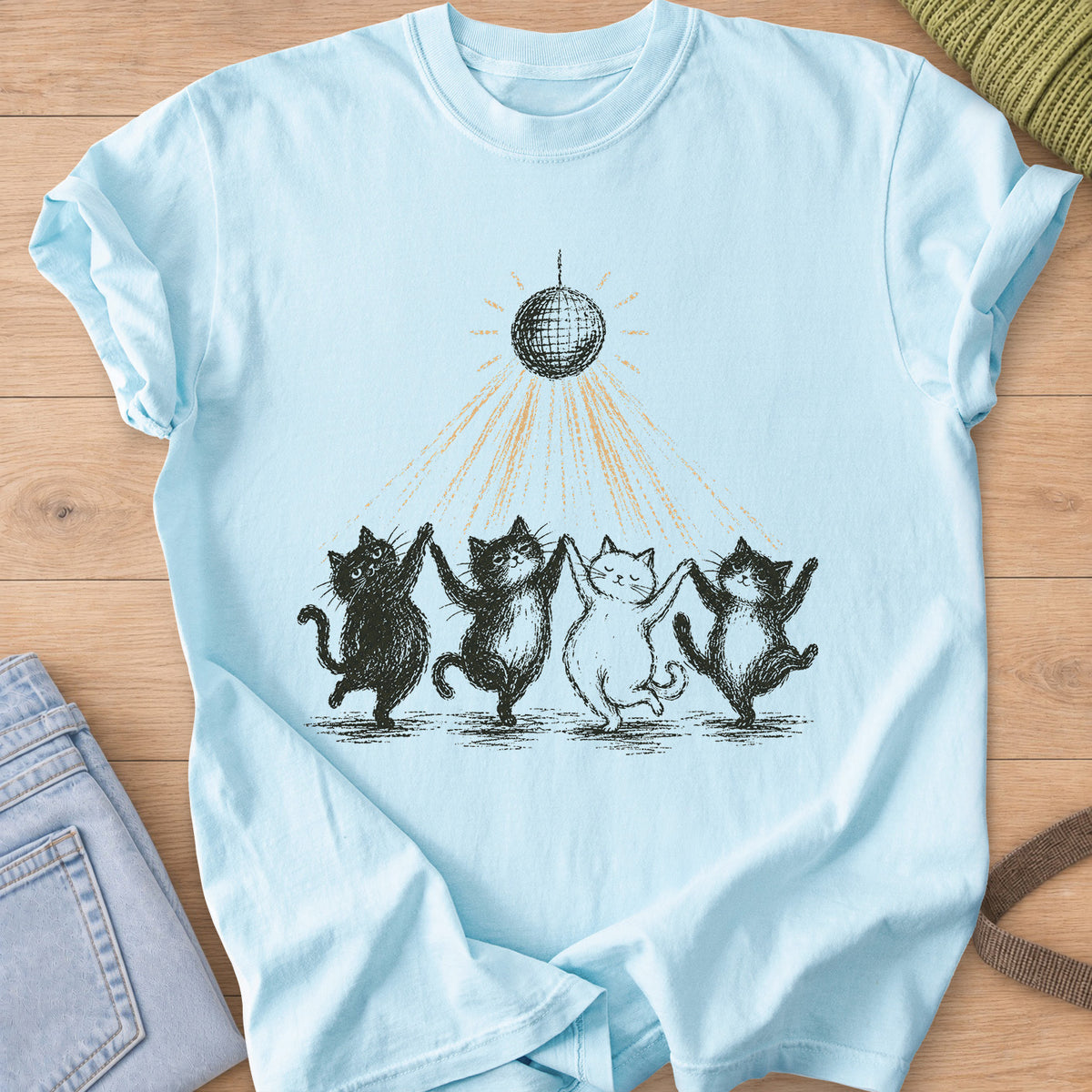 Four cats dancing paw in paw in a line under a disco ball casting light rays, black and gold ink on a Chambray T-Shirt