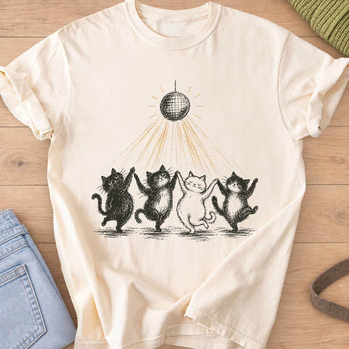 Four cats dancing paw in paw in a line under a disco ball casting light rays, black and gold ink on an Ivory T-Shirt