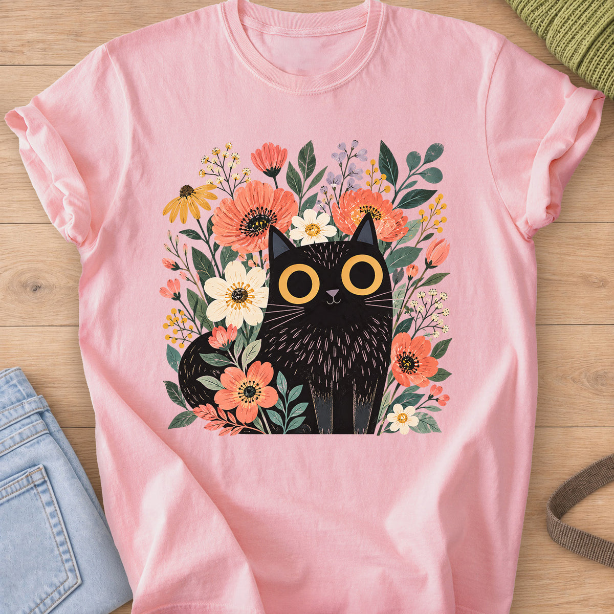 Black cat with big round eyes sitting among wildflowers, daisies and leaves on a Blossom T-Shirt
