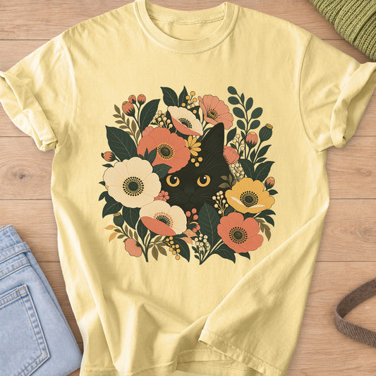 Black cat with round golden eyes peeking out from flowers, leaves and berry clusters on a Butter T-Shirt