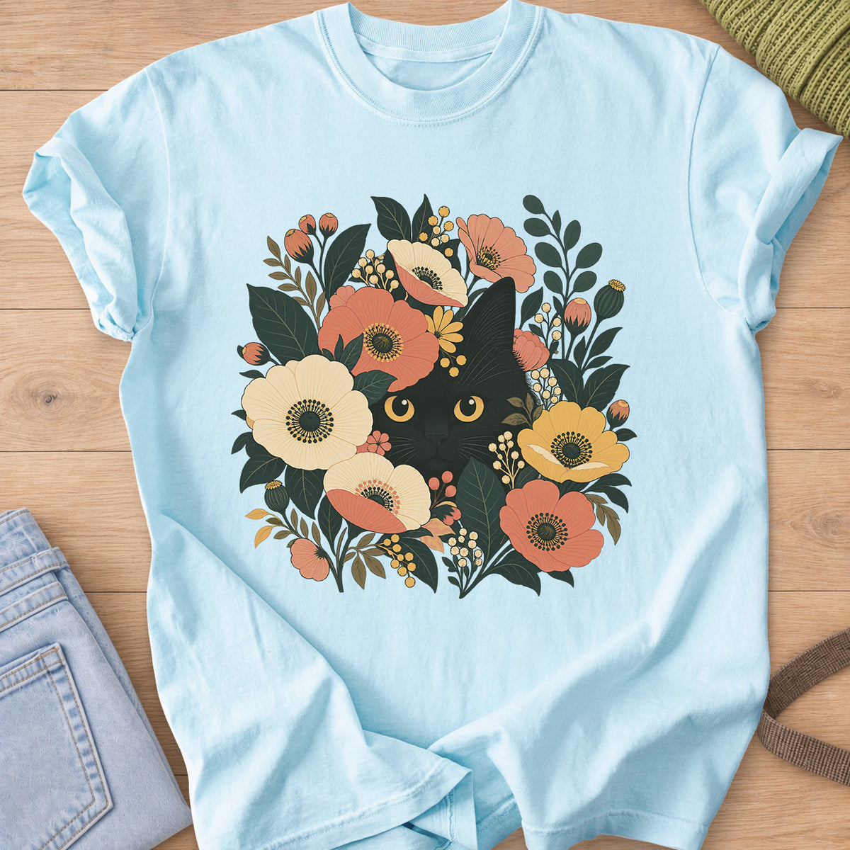 Black cat with round golden eyes peeking out from flowers, leaves and berry clusters on a Chambray T-Shirt