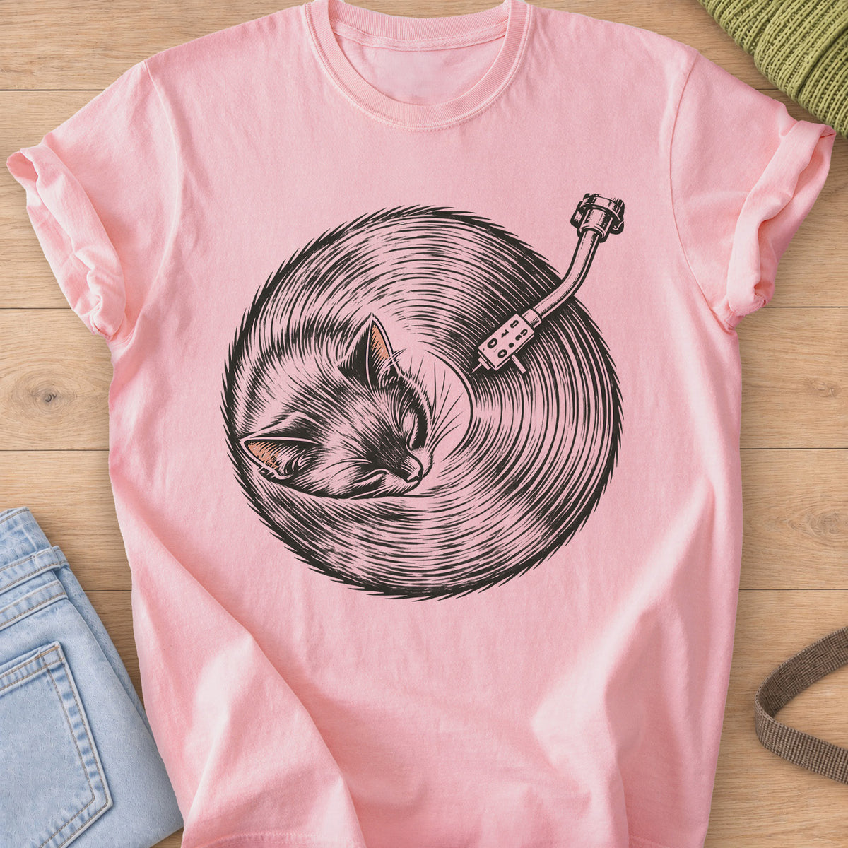 Sleeping cat curled up, its fur forming a vinyl record under a turntable arm, dark charcoal ink on a Blossom T-Shirt