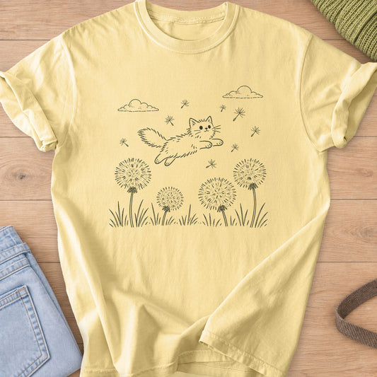 Fluffy cat leaping over dandelion puffs and grass with floating seeds and clouds, dark charcoal ink on a Butter T-Shirt