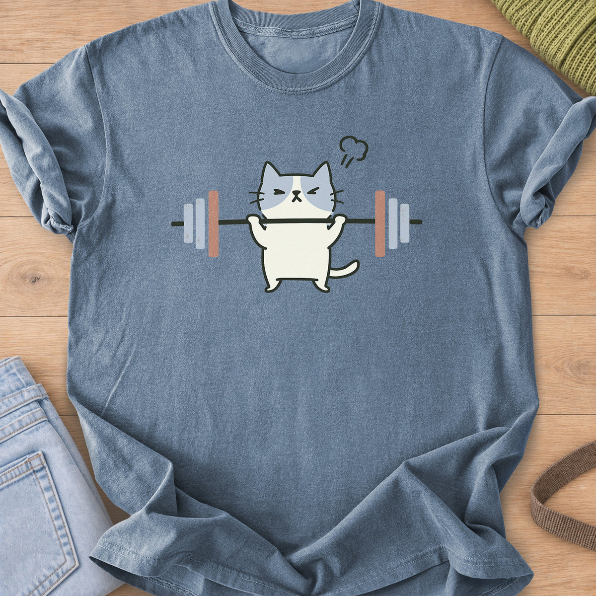 Patched cat squinting as it lifts a barbell, a puff of steam over its head on a Blue Jean T-Shirt