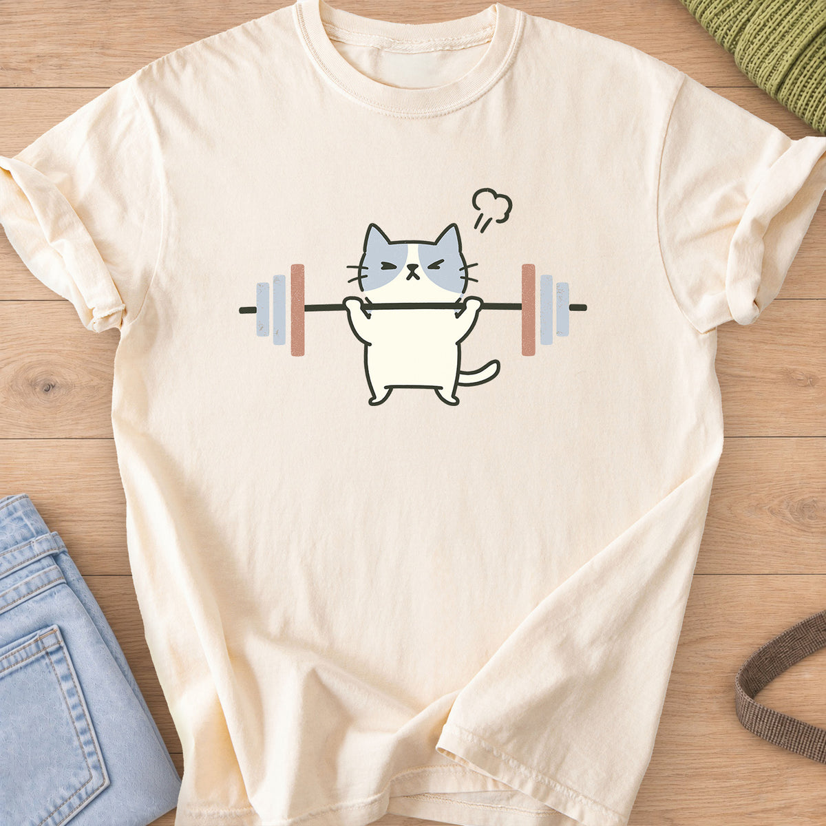 Patched cat squinting as it lifts a barbell, a puff of steam over its head on an Ivory T-Shirt