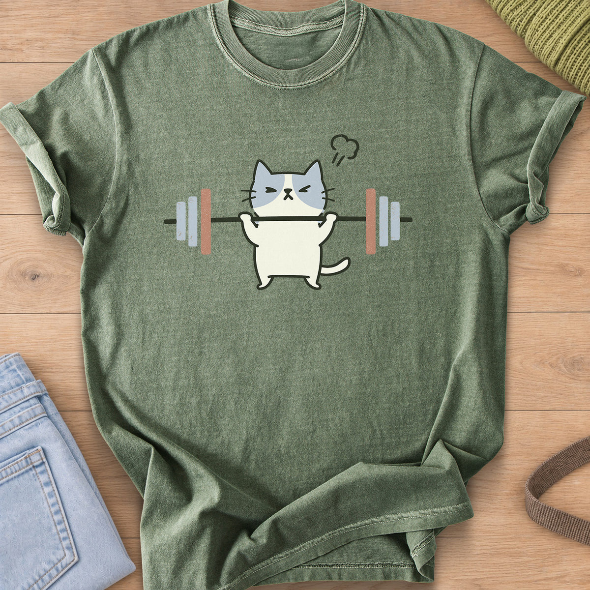 Patched cat squinting as it lifts a barbell, a puff of steam over its head on a Moss T-Shirt