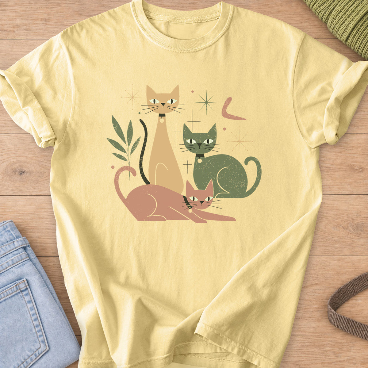 Three mid-century cats with collars posing among starbursts and a leafy sprig on a Butter T-Shirt