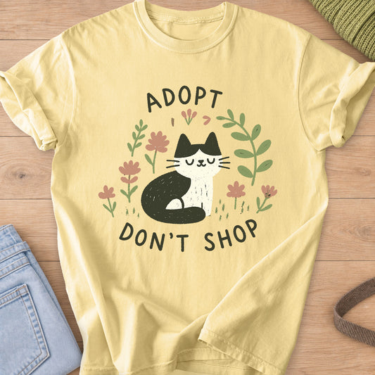 Tuxedo cat sitting with eyes closed among flowers and leaves, "Adopt Don't Shop" on a Butter T-Shirt