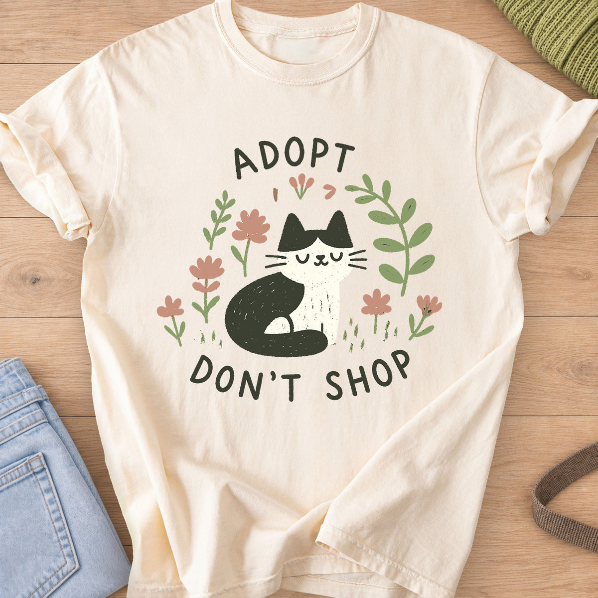 Tuxedo cat sitting with eyes closed among flowers and leaves, "Adopt Don't Shop" on an Ivory T-Shirt