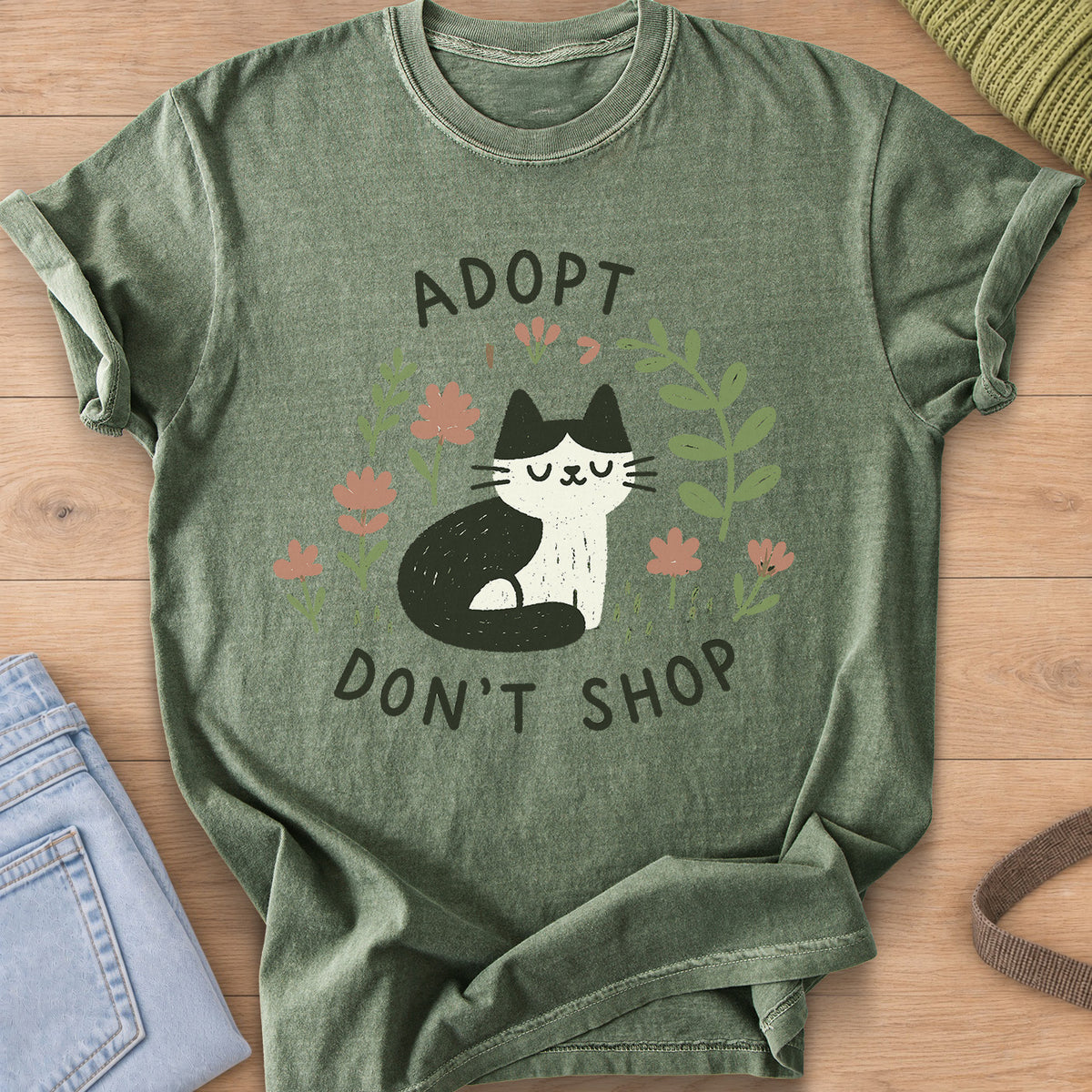 Tuxedo cat sitting with eyes closed among flowers and leaves, "Adopt Don't Shop" on a Moss T-Shirt
