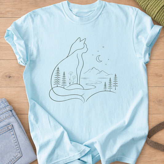 Sitting cat outline with pines and a river inside, facing mountains and a moon, dark charcoal ink on a Chambray T-Shirt